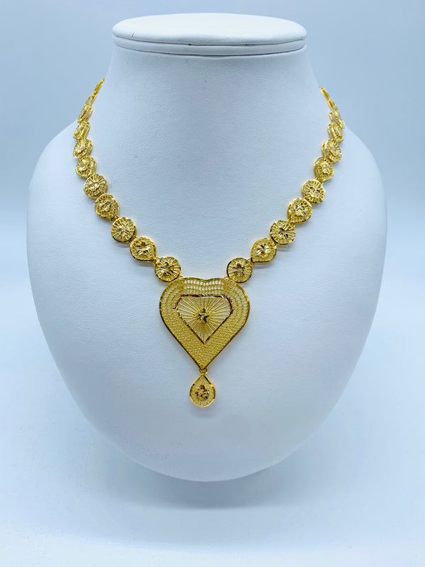 Gold bridal necklace with heart shape dangling drop pendant and chain embellished with a series of alternate circular spikes and drops with round jali pattern.