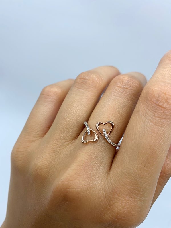 A double-heart diamond ring worn on a female’s tall finger and enhancing the beauty of her hand.